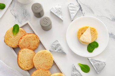 Beyaz mermer zemin üzerinde kızarmış ekmek tabakları ve lezzetli işlenmiş peynir üçgenleri.