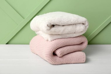 Hafif ahşap masa üzerinde yeni katlanmış battaniyeler Yeni yeşil duvar