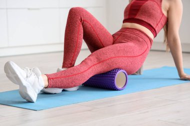 Açık mutfakta yoga minderi üzerinde egzersiz yapan genç bir kadın.