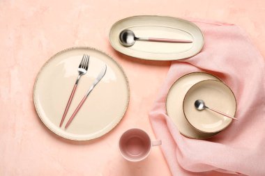 Pembe masada temiz tabak, kase ve çatal bıçak takımı var.