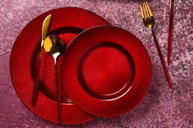 Koyu pembe masa üzerinde çatal bıçak takımı olan temiz tabaklar.