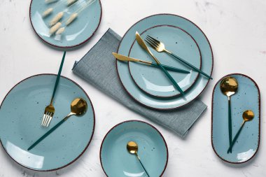 Masa seti, temiz tabaklar, altın çatal bıçak ve beyaz arka planda peçete.