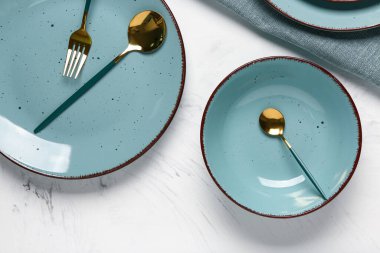 Masa seti, temiz tabaklar, altın çatal bıçak ve beyaz arka planda peçete.