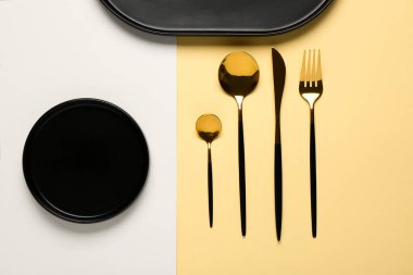 Temiz tabaklar ve bej arka planda altın çatal bıçak takımı.