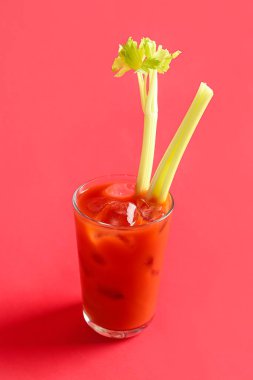 Kırmızı zemin üzerinde kereviz olan bir bardak Bloody Mary.