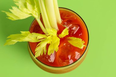 Yeşil zemin üzerinde kereviz olan bir bardak Bloody Mary.