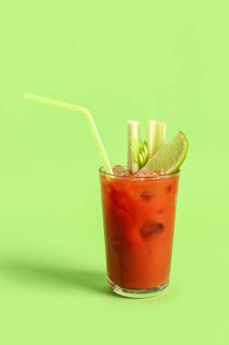 Yeşil zemin üzerinde kereviz ve limon olan bir bardak Bloody Mary.