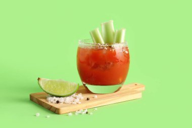 Yeşil arka planda bir bardak Bloody Mary ve kereviz.