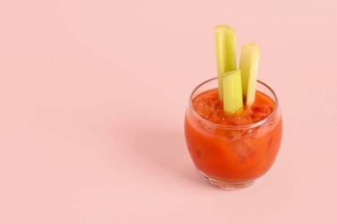 Pembe arka planda kerevizli bir bardak Bloody Mary.