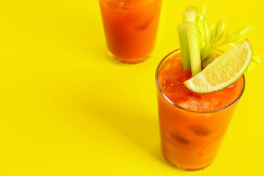 Sarı arka planda kereviz ve limonlu Bloody Mary bardakları.