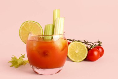 Pembe arka planda kereviz ve limonlu bir bardak Bloody Mary.