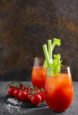 Gri masadaki domatesli ve kerevizli Bloody Mary bardakları