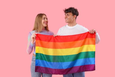 Pembe arka planda LGBT bayrağı olan genç çift