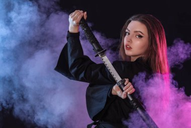 Koyu arkaplanda katana olan güzel genç bir kadın.