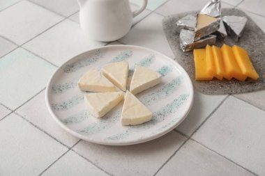 Açık fayans zemin üzerinde lezzetli işlenmiş peynir üçgenleri olan tabak, yakın plan.