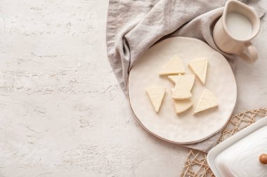 Açık arkaplanda lezzetli işlenmiş peynir ve süt üçgenleri olan bir tabak.