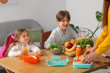 Anne küçük çocukları için mutfakta öğle yemeği hazırlıyor.