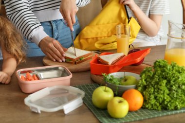 Anne, küçük çocukları için mutfakta öğle yemeği hazırlıyor.