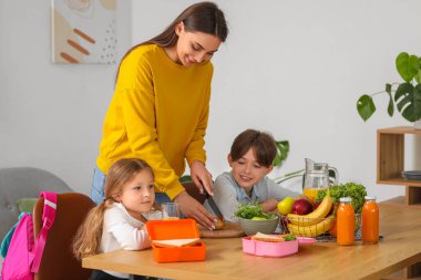 Anne, küçük çocuklarına mutfakta öğle yemeği hazırlıyor.