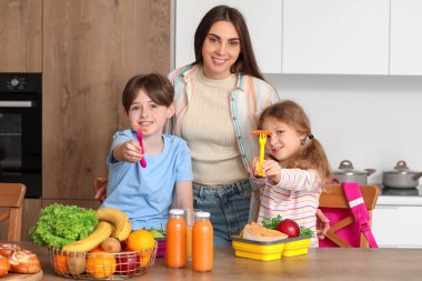 Anne küçük çocukları için mutfakta öğle yemeği hazırlıyor.