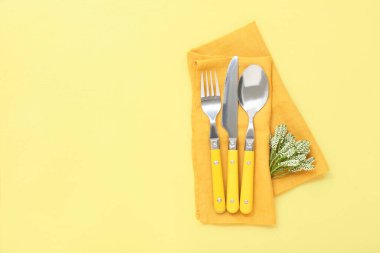 Sarı masa üzerinde portakal rengi peçete ve çiçek dekoru.