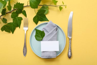 Boş tebrik kartı ve sarı masaya ağaç dalları olan güzel bir masa.