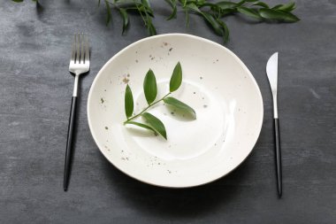 Masanın üzerinde çatal bıçak ve bitki dalları olan güzel bir masa.