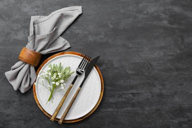 Çatal bıçak takımı ve siyah masa üzerinde çingene çiçekleri olan güzel bir masa.