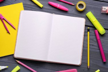 Koyu mavi ahşap arka planda farklı okul kırtasiyesine sahip defterler