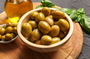 Siyah zemin üzerinde olgun zeytinlerle dolu bir kase.