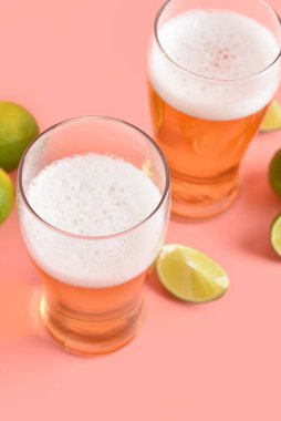 Pembe arka planda limonlu soğuk bira bardakları