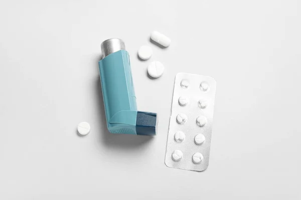 灰色の背景に喘息吸入器と薬 — ストック写真