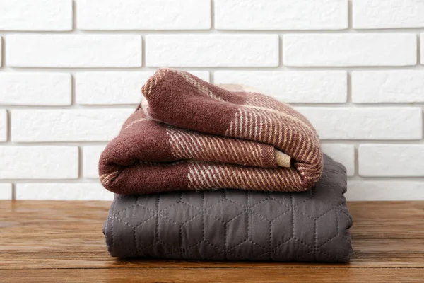 New Soft Folded Blankets Wooden Table Light Brick Wall — Stock Photo, Image