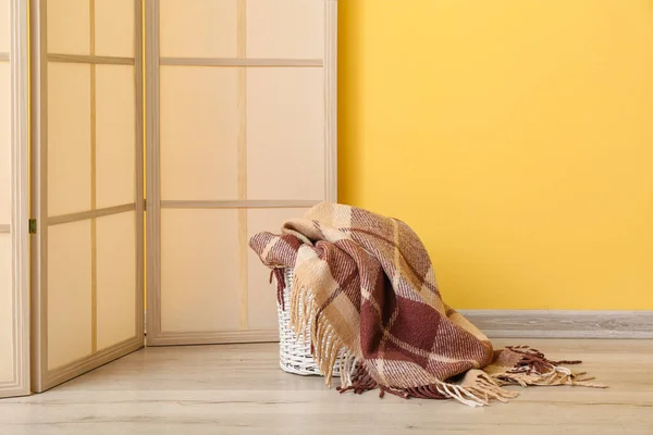 Καλάθι Νέα Μαλακή Κουβέρτα Και Πτυσσόμενη Οθόνη Κοντά Κίτρινο Τοίχο — Φωτογραφία Αρχείου