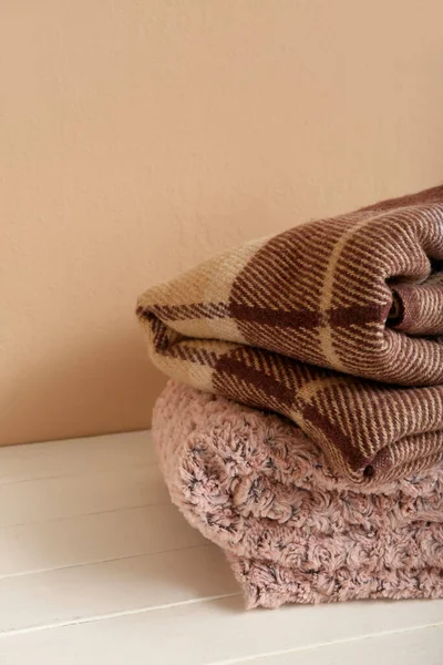 ベージュの壁の近くのテーブルの上に新しい柔らかい折り畳まれた毛布 — ストック写真