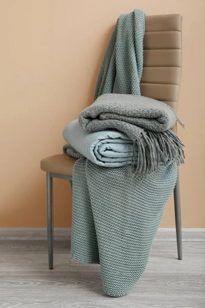 Novos Cobertores Dobrados Macios Cadeira Perto Parede Bege Quarto — Fotografia de Stock