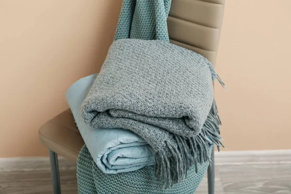 Bej duvarın yanındaki sandalyeye yeni katlanmış battaniyeler, yakın plan.