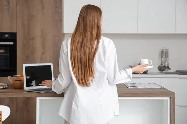Жінка Працює Сучасному Ноутбуці Тримає Чашку Кави Легкій Кухні — стокове фото