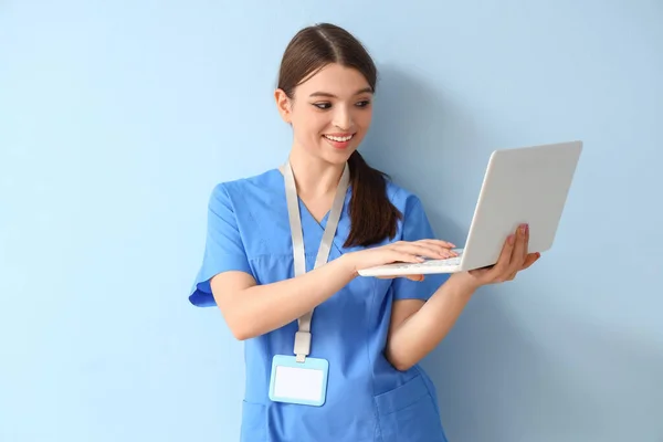与蓝色背景笔记本电脑一起工作的女医务实习生 — 图库照片