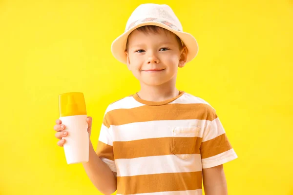 黄色の背景に日焼け止めクリームのボトルを持つ小さな男の子 — ストック写真