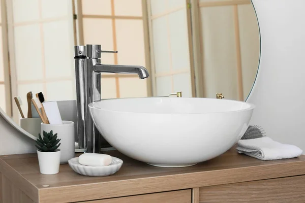 浴室木柜上的水槽 有牙刷的杯子 肥皂棒和室内植物 — 图库照片