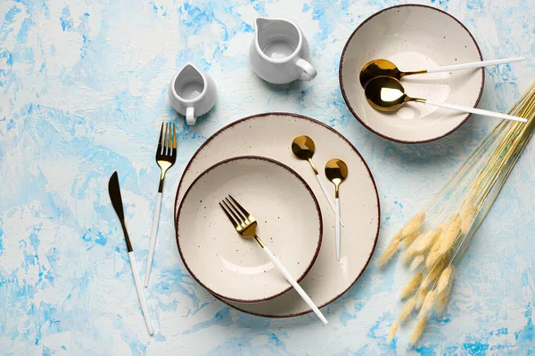 黄金のカトラリーと青のグランジテーブルの上に乾燥したラグジュラスときれいなプレート — ストック写真