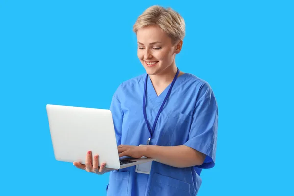 Female Medical Intern Using Laptop Blue Background — стоковое фото