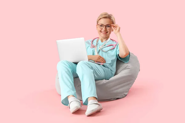 在粉色背景下使用笔记本电脑的女实习生 — 图库照片