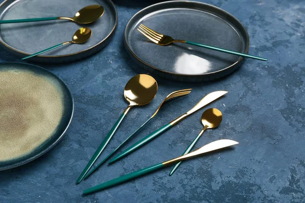 Tischdekoration Mit Sauberen Tellern Und Goldenem Besteck Auf Blauem Grunge — Stockfoto