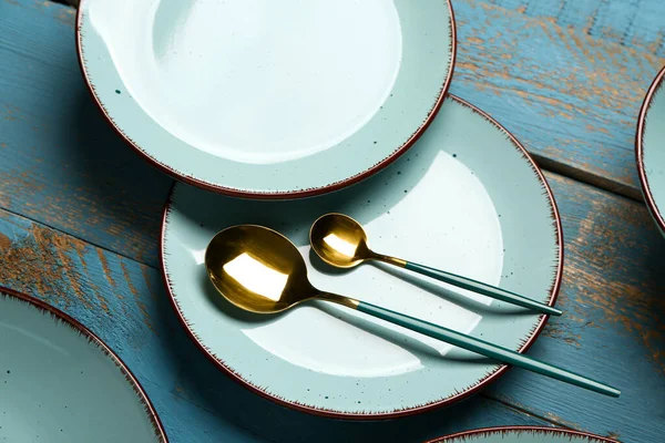 Saubere Teller Und Goldene Löffel Auf Blauem Holztisch — Stockfoto