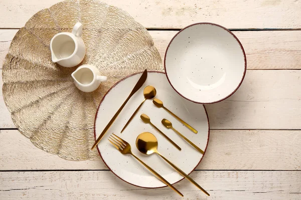 洁白木桌上的干净盘子 一套金制餐具 碗和壶 — 图库照片