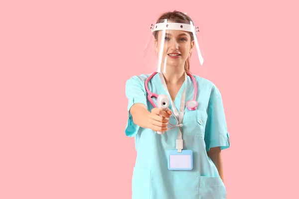 Žena Lékařská Stážistka Ochranné Masce Infračerveným Teploměrem Růžovém Pozadí — Stock fotografie