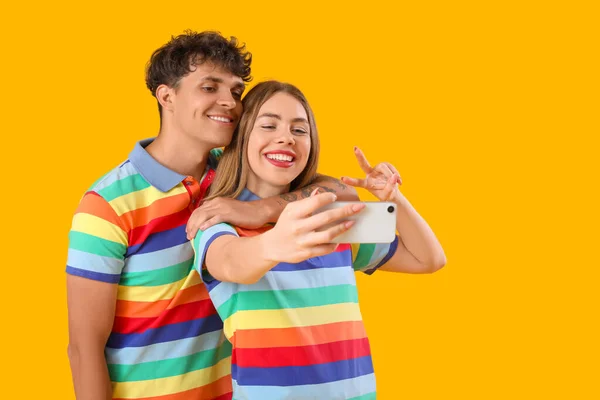Młoda Para Tęczowych Koszulach Robi Selfie Żółtym Tle Miesiąc Pychy — Zdjęcie stockowe