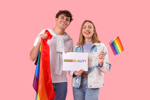 年轻夫妇手中拿着粉红背景的文字平等和Lgbt旗帜的纸 — 图库照片